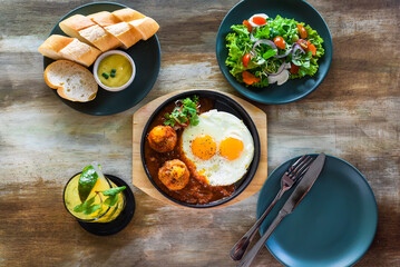 Vietnamese Banh mi chao dish with salted egg yolk meatballs, tomatoes relish, fried eggs and served...