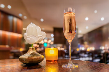 A glass of sparkling rose champagne wine on a table at a fine dining restaurant decorated with a...