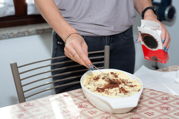 woman's hands prepares tiramisu. Typical Italian dessert