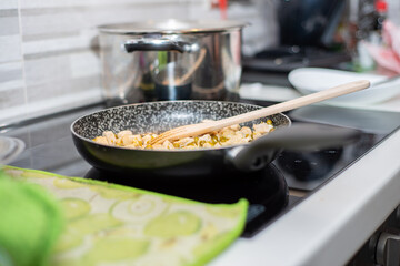 Chicken and peas are cooking in a pan on an induction cooker. Typical Italian cuisine