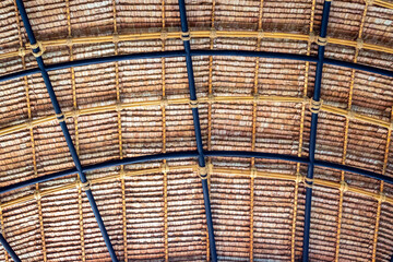 Beautiful thatched roof surface detail of mixed materials pattern structure by weave pile straw with steel bars. .Roof​ made​ of​ straw. Pattern of under bamboo roof frame..Wooden thatched ceiling.