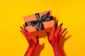 Spooky, red monster hands hold a gift