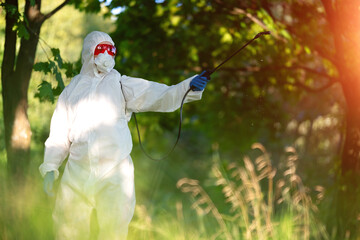 A worker sprays pesticides in an open park on the lawn. Pest control