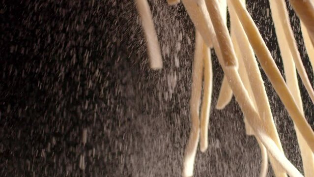 A chef holds strands of raw pasta