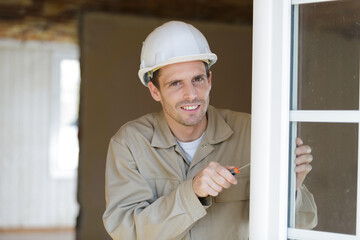 male glazier installing window with screwdriver