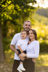 Fototapeta premium Summer sunny day for a young family, dad, mom and little son became joyful and happy in park