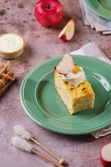 Sliced kugel, casserole of noodles, cottage cheese, apples and raisins on a green plate on a brown concrete background. Jewish cuisine. Noodle dishes.