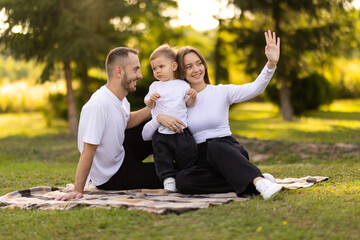 Young cute little son with parents greeting in park with parents.