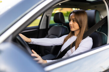 Beautiful young smiling woman driving her car.