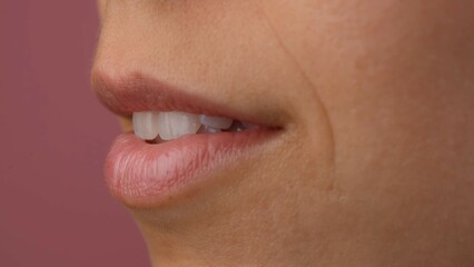 Closeup of female model pink lips, open mouth with teeth visible. Macro shot of beautiful caucasian woman part of the face without makeup, natural view.