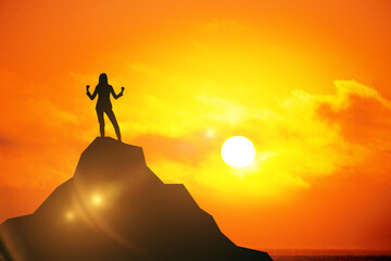 Silhouette of female celebrating success on abstract mountain top at sunset.