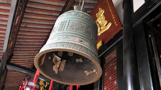 Large brass bell hanging under the roof in Wenshu monastery, Chengdu, China. This ancient and majestic bell, adorned with intricate details and symbolic engravings, exudes a sense of spirituality.