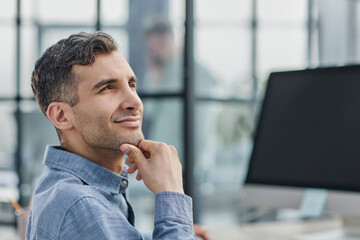 Portrait of cheerful male student enjoying learning in coworking office using laptop computer for research