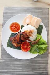 spicy chicken roasted with hot rice and raw vegetables,cucumbar,tomato, served on banana leaf