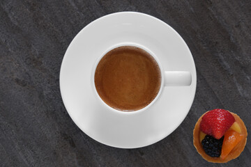 White cup, fruit tartlets on a black background. Coffee on black. White cup of coffee on a dark background flat lay.
