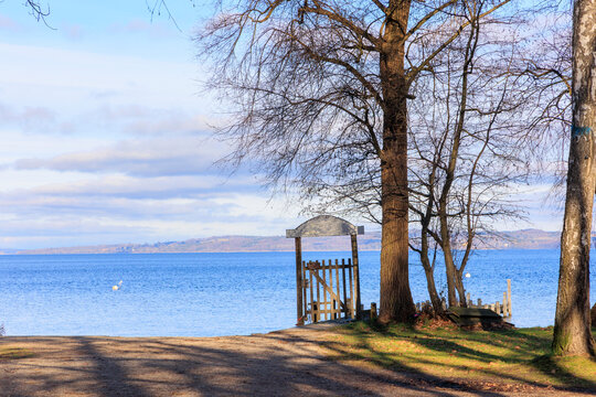 Gate with a weathered sign on the shore of Ammersee under trees in winter near Die&szlig;en in Bavaria