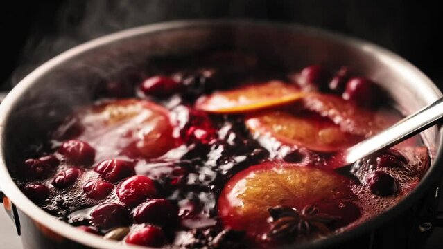 Mulled wine is boiling in a saucepan. Traditional hot autumn or winter holiday drink made from red wine with spices and oranges. Stock video 4k