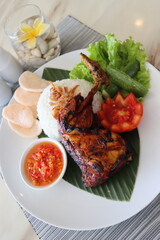 spicy chicken roasted with hot rice and raw vegetables,cucumbar,tomato, served on banana leaf