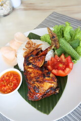 spicy chicken roasted with hot rice and raw vegetables,cucumbar,tomato, served on banana leaf