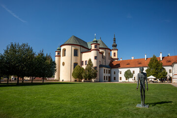 Fototapeta na wymiar Gothic medieval church, Piarist Church of the Finding of the Holy Cross at sunny summer day, Monastery Garden with sculptures, Litomysl, Czech Republic