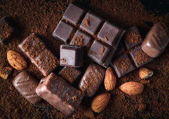 Heap of various chocolate candies closeup on a black wooden table in the dark