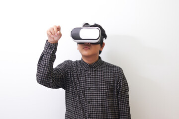 Portrait of Asian man in black plaid shirt using Virtual Reality (VR) glasses and trying to touch...