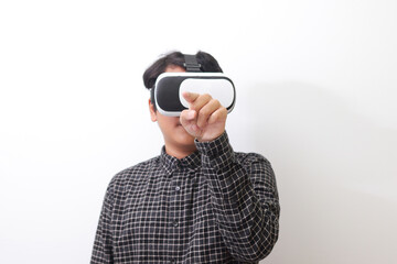 Portrait of Asian man in black plaid shirt using Virtual Reality (VR) glasses and trying to touch...
