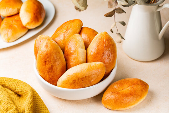Pirozhki, piroshki. Homemade baked yeast leavened boat shaped buns with braised cabbage fillings. Pirozhki are a popular street food and comfort food in Eastern Europe. Light background.