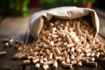 Tuinposter Sack of wood pellets spilled on rustic wooden floor, ecology concept, renewable energy, economy © Carlos Cairo