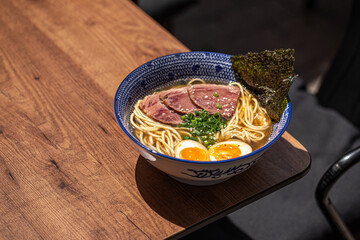 Bowl of japanese ramen noodle soup with beef pastrami on cafe table - Powered by Adobe