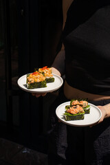 Woman holding plates of japanese hand sushi rolls