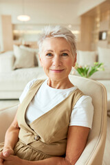 Portrait of elegant beautiful positive senior good-looking female HR sitting in armchair in cozy...