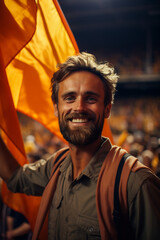 A happy man waves a flag in the stands of a stadium