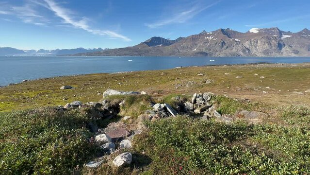 Static camera view at historical remains of Thule-culture winter houses on Denmark Island, Scoresbysund, Greenland.