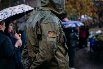 A Ukrainian serviceman in the rain at the funeral of his comrade who died during Russia's invasion...