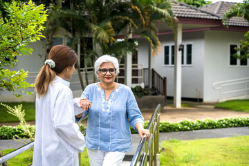 Elderly woman walking in home care garden with care giver nurse