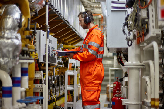 Marine engineer checking parameters of main engine in engine room.