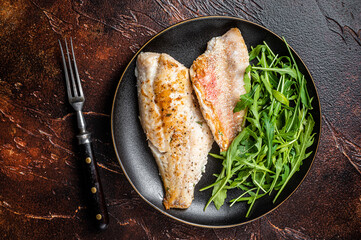 Roasted Snapper, sea red perch fillet on a plate with salad. Dark background. Top view