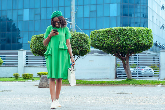 colorful young woman in a green dress engrossed in her cell phone