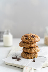 Healthy oatmeal cookies with banana, nuts, dark chocolate and flaxseed on a wooden board on a light background. Delicious homemade vegan food recipe. Stack of oatmeal biscuits. Copy space