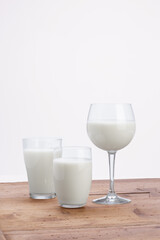 glasses of milk on rustic milk table with white background