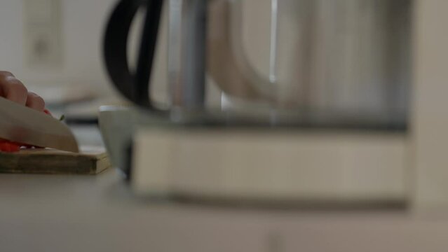 Close up of a woman chopping a red pepper with a chef knife in a small kitchen. Panasonic Lumix S5, with a 75mm lens.