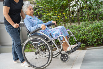 Obraz premium Caregiver help and care Asian senior woman patient sitting on wheelchair to ramp in nursing hospital, healthy strong medical concept.