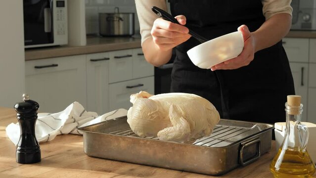 A woman in the kitchen is marinating a turkey before roasting it in the oven for a Thanksgiving or Christmas dinner. Turkey or chicken cooking process stock video 4k