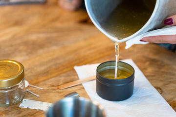 Aromatic candle workshop. Woman pouring melted soy wax.