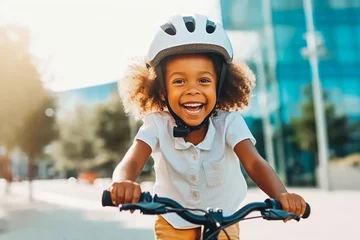 Selbstklebende Fototapeten Little african american girl riding her bike with a safety helmet and enjoying a fun ride through the city, childhood adventures © VisualProduction
