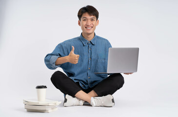 Full body Asian male student using laptop on white background