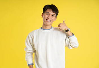 Portrait of young Asian man wearing sweater and posing on yellow background