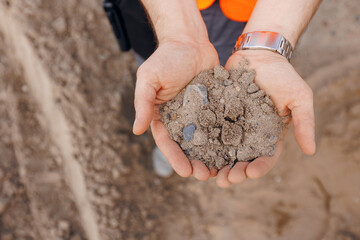 Worker engineer checks quality of sand at quarry. Industrial construction site concept