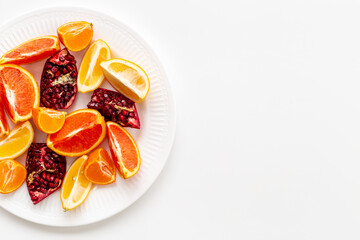 Layout of citrus fruits on white plate top view